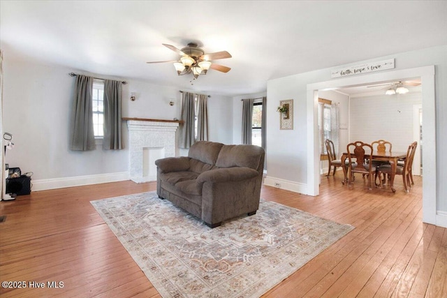 living room featuring ceiling fan, hardwood / wood-style floors, and a brick fireplace