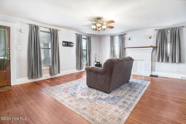 living room with hardwood / wood-style flooring, a fireplace, and ceiling fan