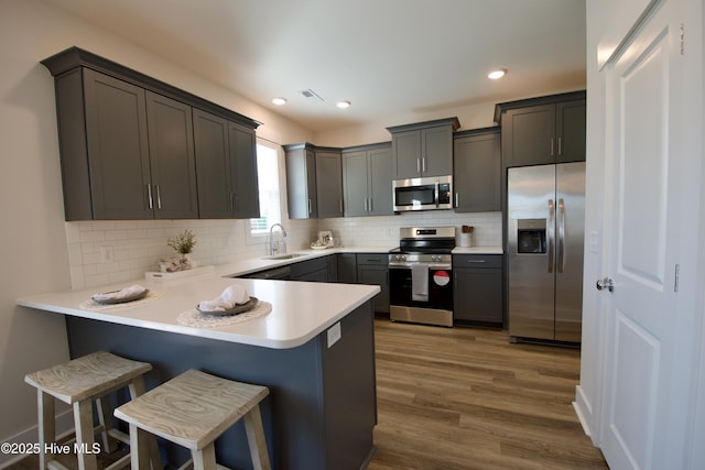 kitchen with a breakfast bar, stainless steel appliances, kitchen peninsula, and sink