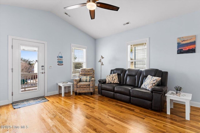 living room featuring lofted ceiling, a healthy amount of sunlight, visible vents, and light wood finished floors