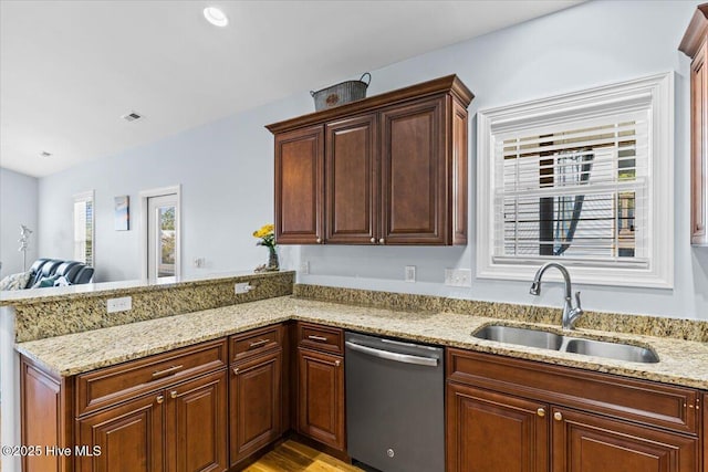 kitchen featuring visible vents, light stone countertops, a peninsula, stainless steel dishwasher, and a sink