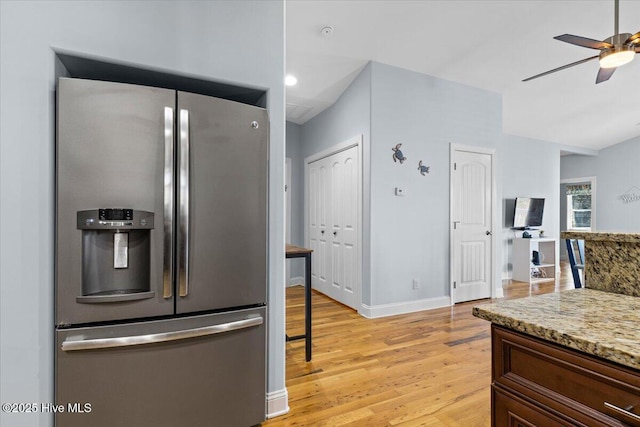 kitchen with light wood-type flooring, light stone counters, stainless steel fridge with ice dispenser, baseboards, and ceiling fan