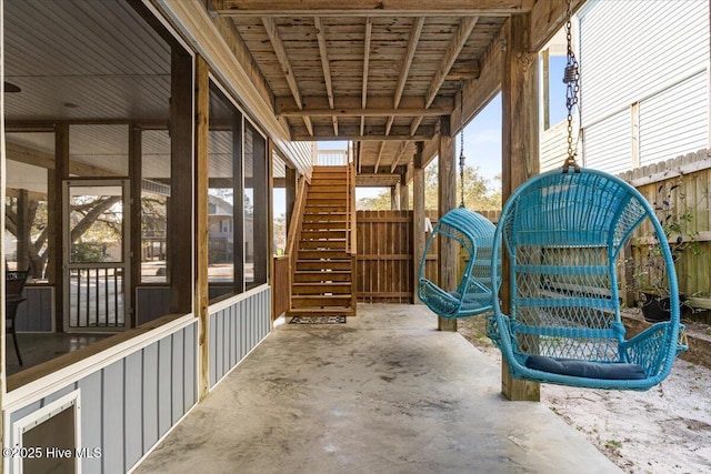 view of patio / terrace featuring stairway, fence, and a sunroom