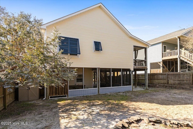 back of property with fence and a sunroom