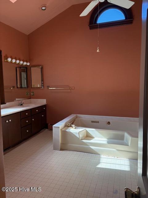 bathroom featuring ceiling fan, vanity, vaulted ceiling, and a tub