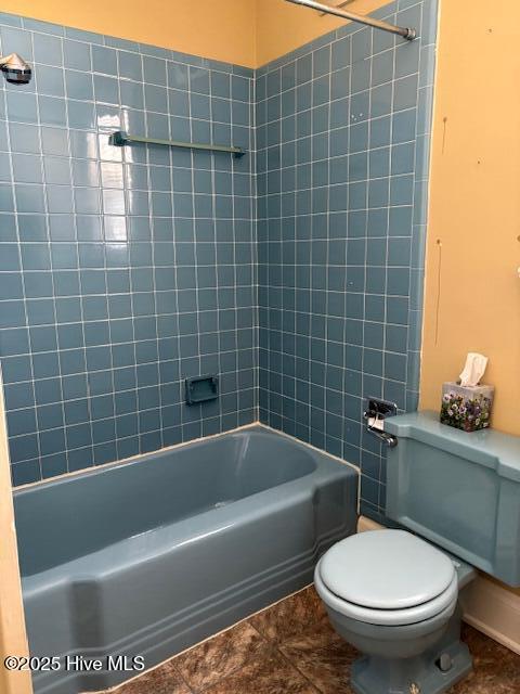 bathroom with tile patterned flooring, tiled shower / bath combo, and toilet