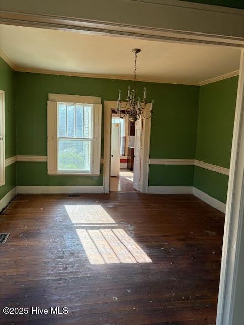 unfurnished dining area featuring ornamental molding, dark wood-type flooring, and an inviting chandelier