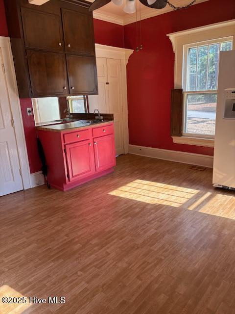 kitchen with crown molding, white refrigerator with ice dispenser, ceiling fan, and light hardwood / wood-style flooring