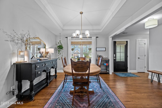 dining room featuring a raised ceiling, ornamental molding, dark wood-type flooring, and a notable chandelier