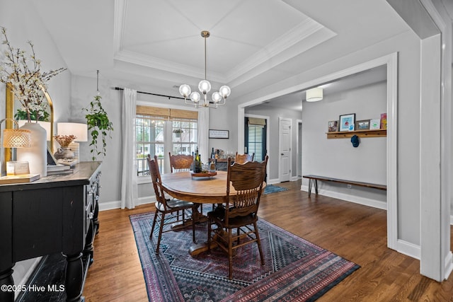 dining room with dark hardwood / wood-style floors, a notable chandelier, a tray ceiling, and crown molding