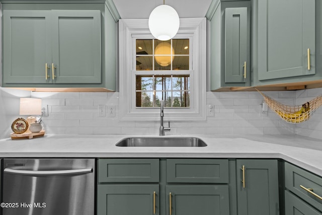 kitchen featuring sink, green cabinetry, decorative light fixtures, stainless steel dishwasher, and light stone countertops