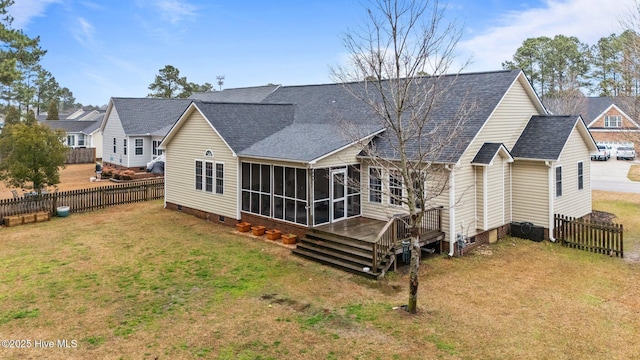 back of property featuring a lawn, a sunroom, and a deck