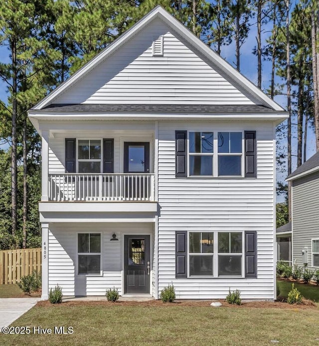 view of front of house with a front yard, fence, and a balcony