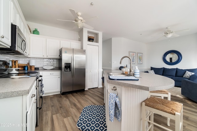 kitchen with sink, a breakfast bar area, white cabinetry, a center island with sink, and appliances with stainless steel finishes