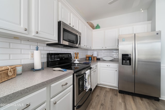 kitchen with white cabinetry, wood-type flooring, decorative backsplash, ceiling fan, and stainless steel appliances