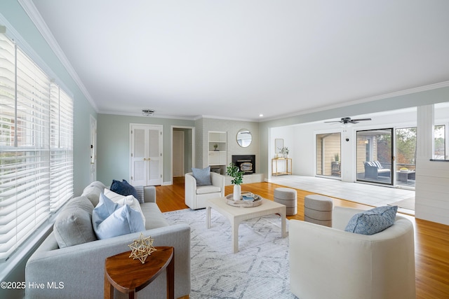 living room with crown molding, a fireplace, and light hardwood / wood-style floors