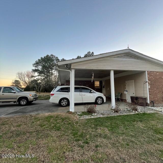 parking at dusk with a carport and a lawn