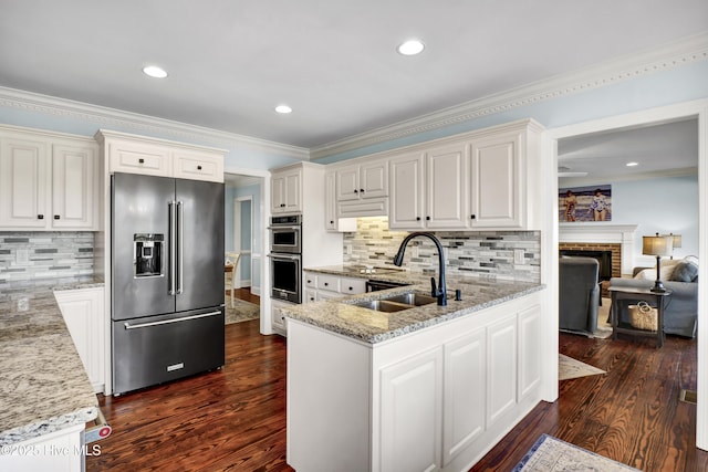 kitchen with light stone countertops, high end refrigerator, stainless steel double oven, and kitchen peninsula