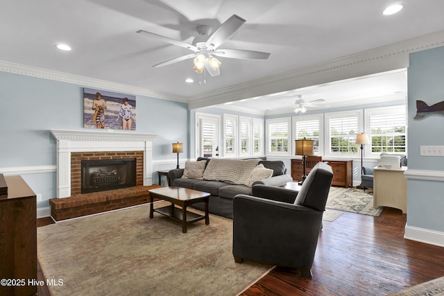 living room with a fireplace, dark wood-type flooring, ornamental molding, and ceiling fan