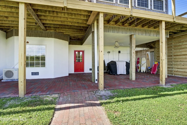 view of exterior entry with a yard, ac unit, and a patio