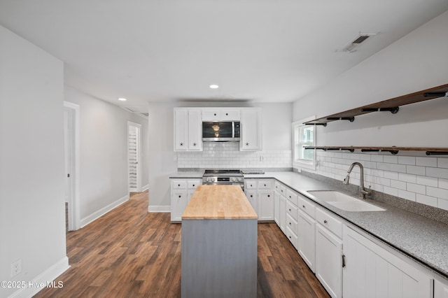 kitchen featuring a kitchen island, appliances with stainless steel finishes, sink, white cabinets, and wooden counters