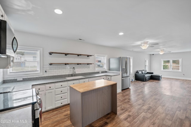 kitchen with sink, white cabinetry, a center island, hardwood / wood-style flooring, and stainless steel appliances