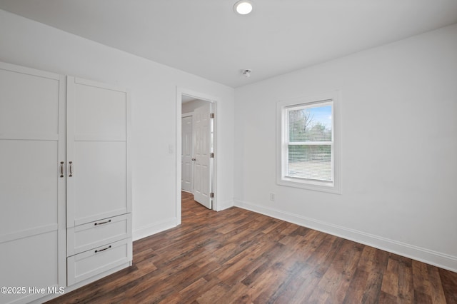 unfurnished bedroom with dark wood-type flooring and a closet