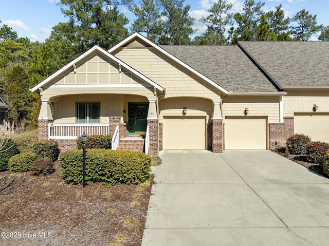 craftsman-style house with a porch, concrete driveway, brick siding, and a garage