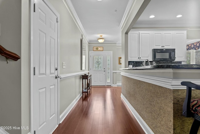 interior space featuring black microwave, dark wood-style flooring, white cabinets, dark countertops, and crown molding