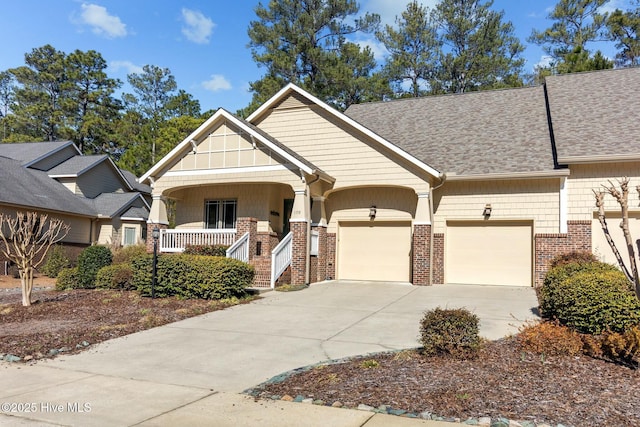 craftsman house featuring covered porch, a garage, brick siding, a shingled roof, and driveway