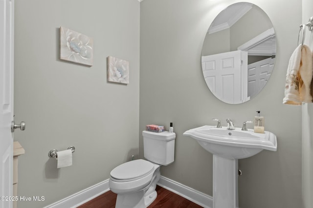 half bath featuring a sink, wood finished floors, toilet, and baseboards