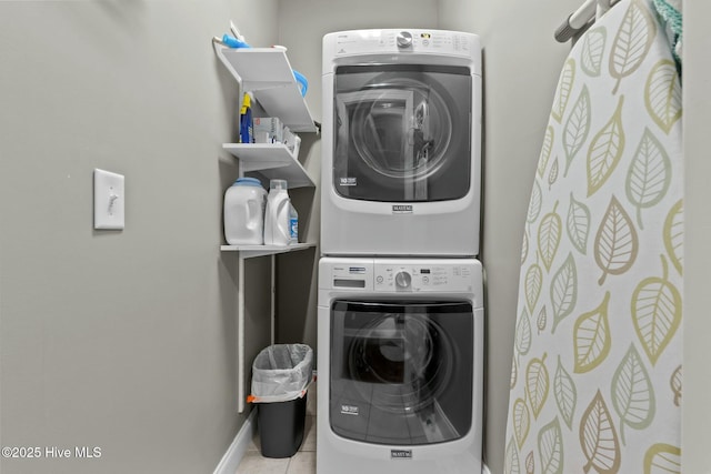 laundry room featuring stacked washer / drying machine, laundry area, light tile patterned flooring, and baseboards