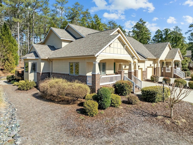 craftsman-style house featuring brick siding, a porch, and a shingled roof