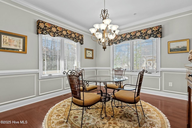 dining room with ornamental molding, a wainscoted wall, dark wood finished floors, and an inviting chandelier