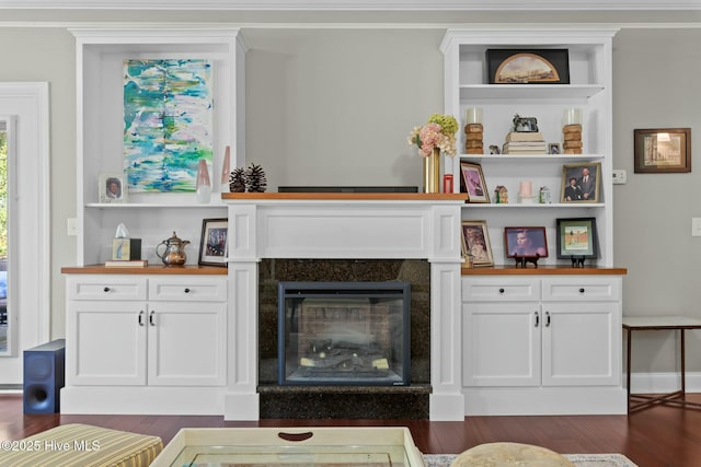 living room with ornamental molding, dark wood-style flooring, and a glass covered fireplace