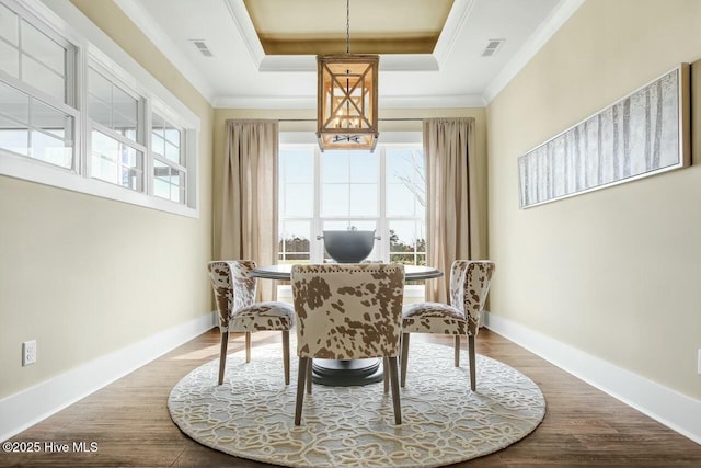 dining room featuring wood-type flooring, ornamental molding, and a raised ceiling