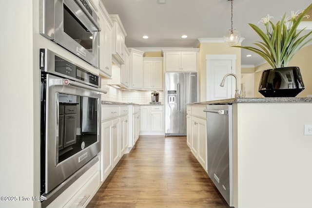 kitchen featuring decorative light fixtures, decorative backsplash, stainless steel appliances, and white cabinets