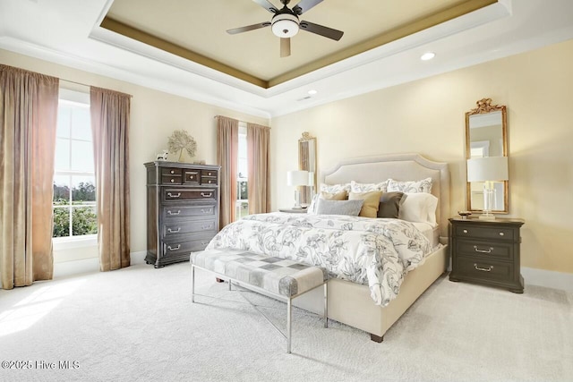 bedroom with light colored carpet, ceiling fan, and a tray ceiling