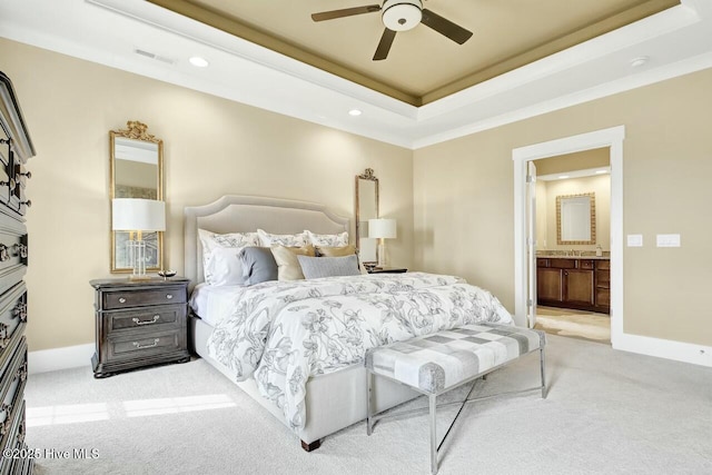 carpeted bedroom with crown molding, ceiling fan, ensuite bathroom, and a tray ceiling