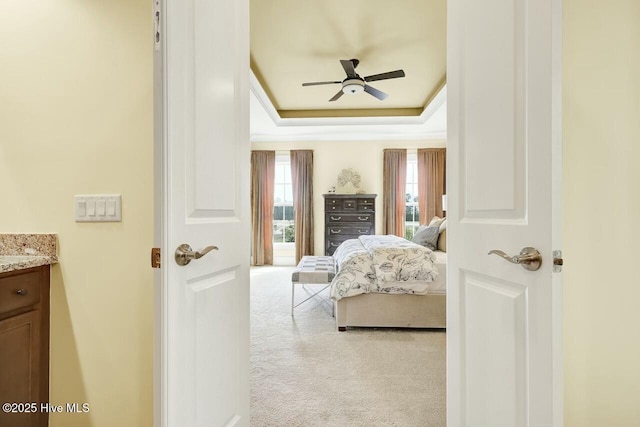 carpeted bedroom featuring a raised ceiling and ceiling fan