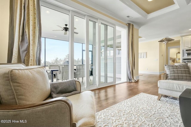 living area with hardwood / wood-style flooring, crown molding, and ceiling fan