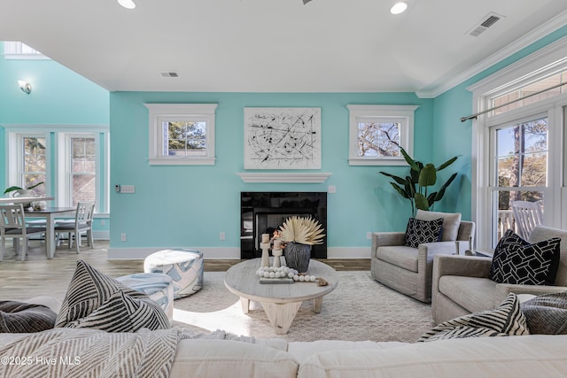 living room with baseboards, visible vents, a tiled fireplace, and wood finished floors