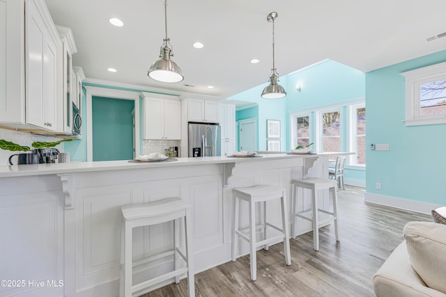 kitchen featuring light countertops, white cabinetry, appliances with stainless steel finishes, visible vents, and decorative backsplash