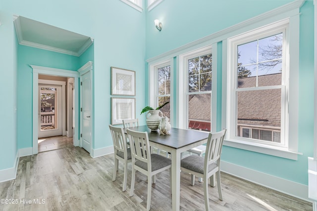 dining space with ornamental molding, baseboards, light wood finished floors, and a wealth of natural light
