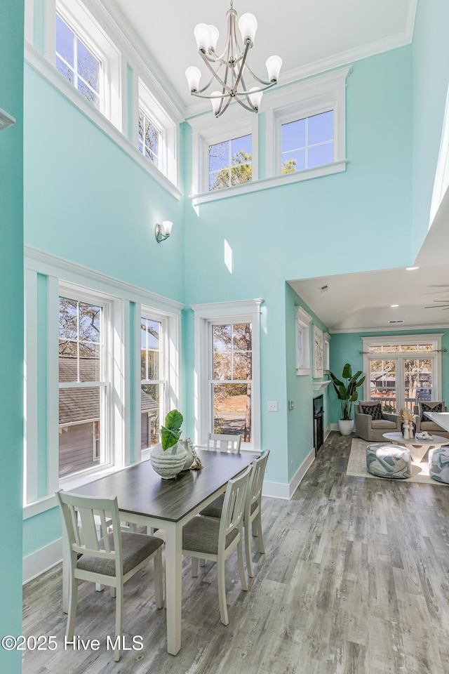 dining room featuring baseboards, ornamental molding, a chandelier, and light wood-type flooring