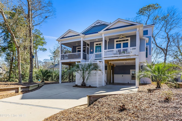 coastal home featuring ceiling fan, driveway, a carport, and covered porch