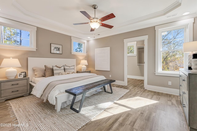 bedroom featuring ornamental molding, a tray ceiling, and light wood finished floors