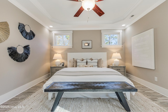 bedroom with ornamental molding, visible vents, multiple windows, and a raised ceiling