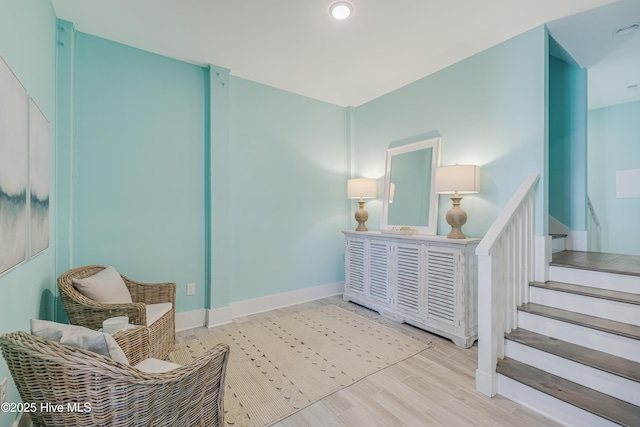 sitting room featuring baseboards, wood finished floors, and stairway