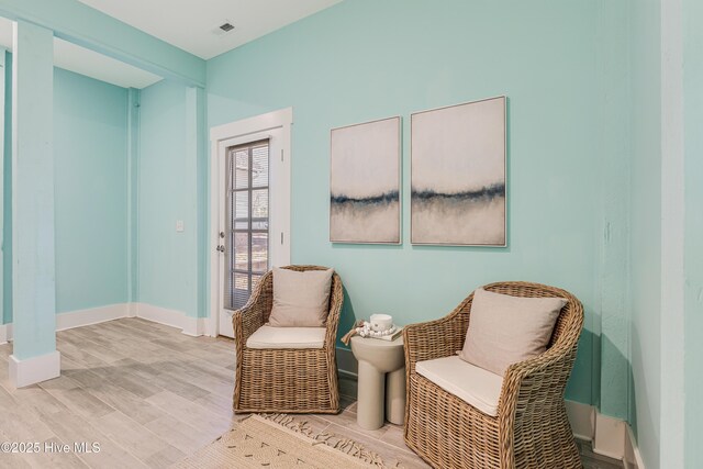 living area featuring baseboards, visible vents, and wood finished floors